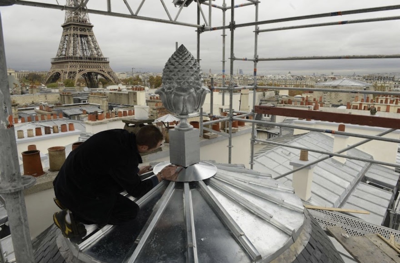 Artisan travaillant sur une toiture parisienne avec la Tour Eiffel en arrière-plan